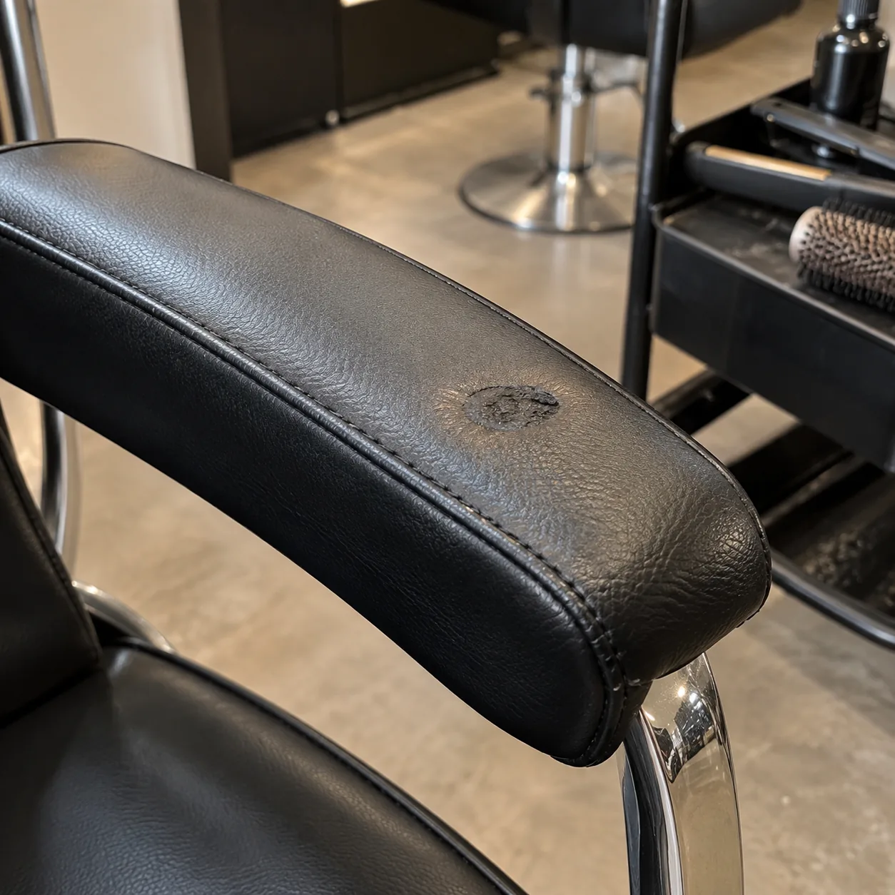 A small heat mark from a hot tool on a salon chair arm pad