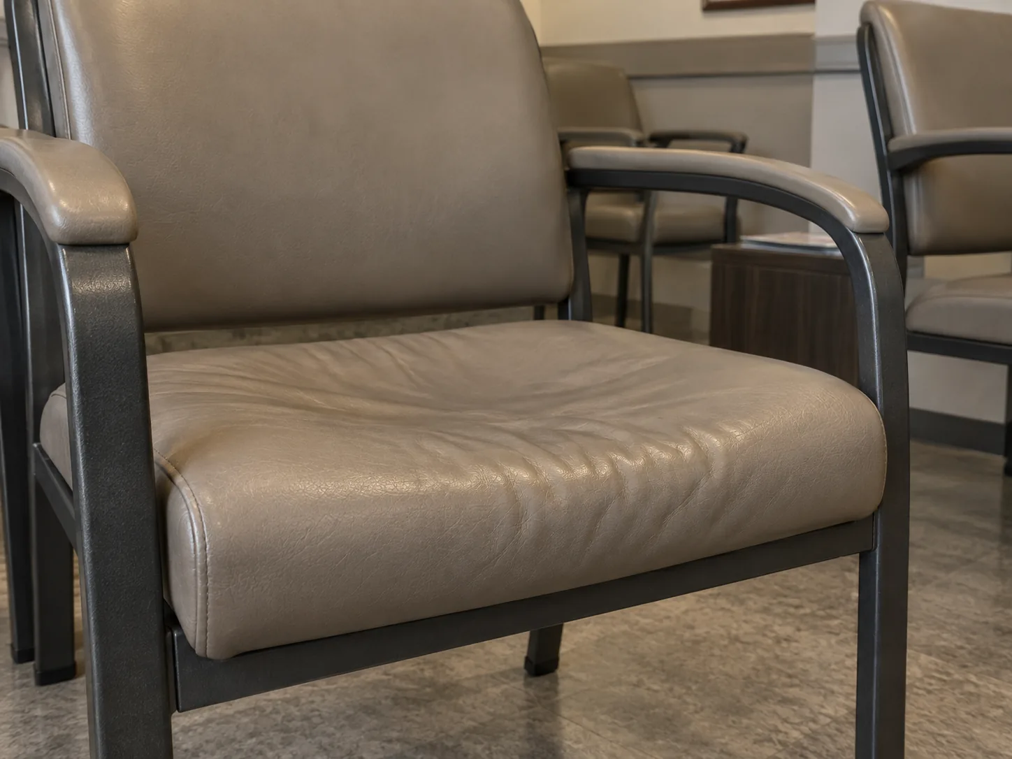 A sagging, creased waiting room chair seat with flattened foam