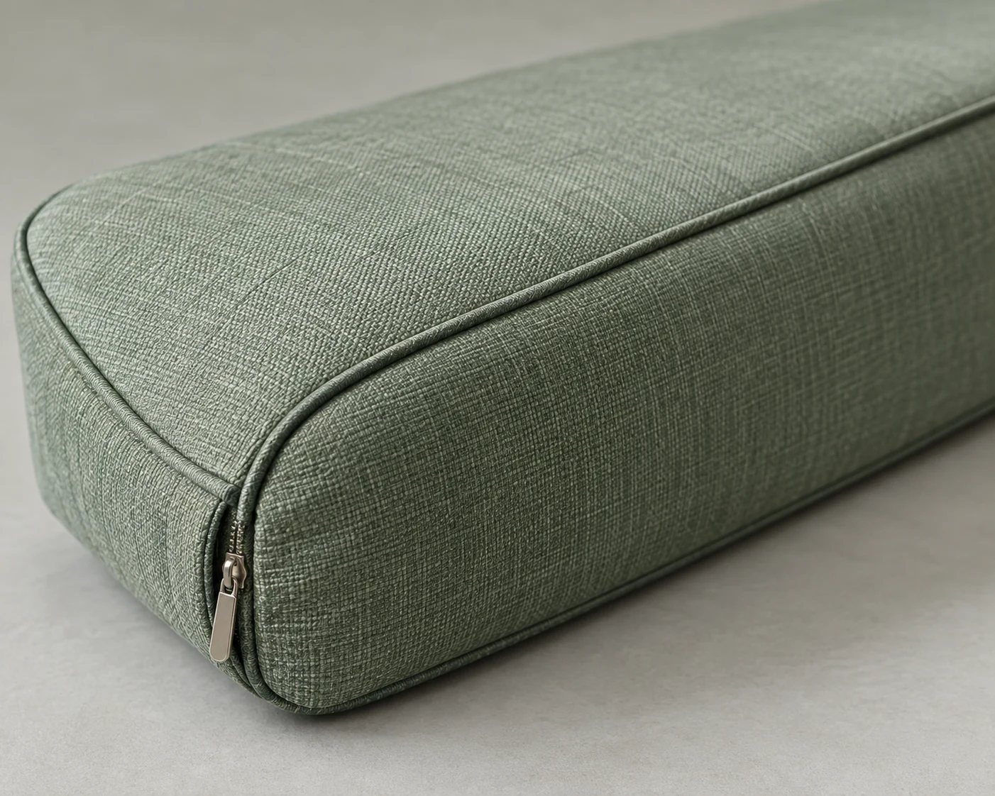 Green outdoor bolster cushion with a zipper closing the end panel