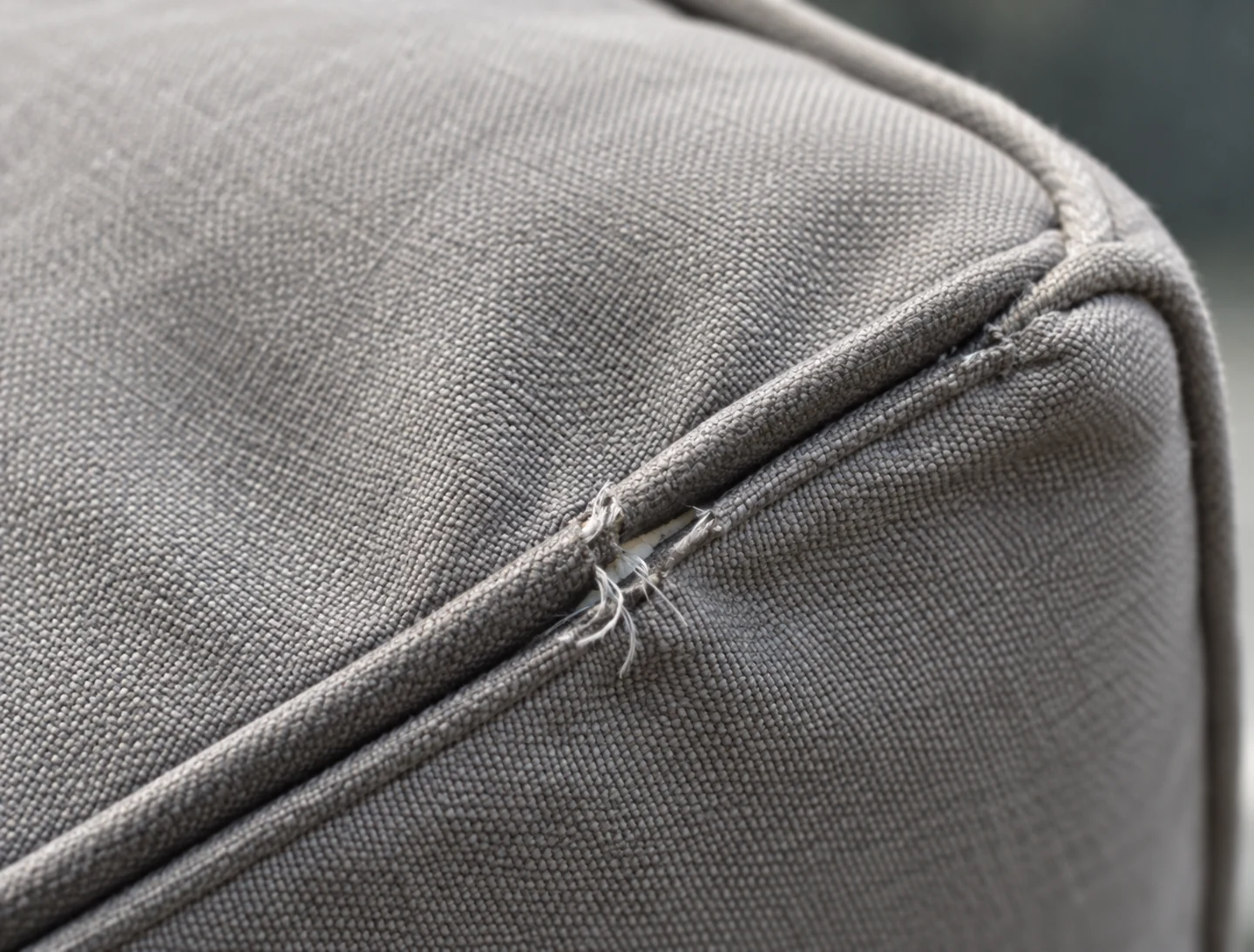 Zipper pull tucked into the corner of a grey outdoor cushion