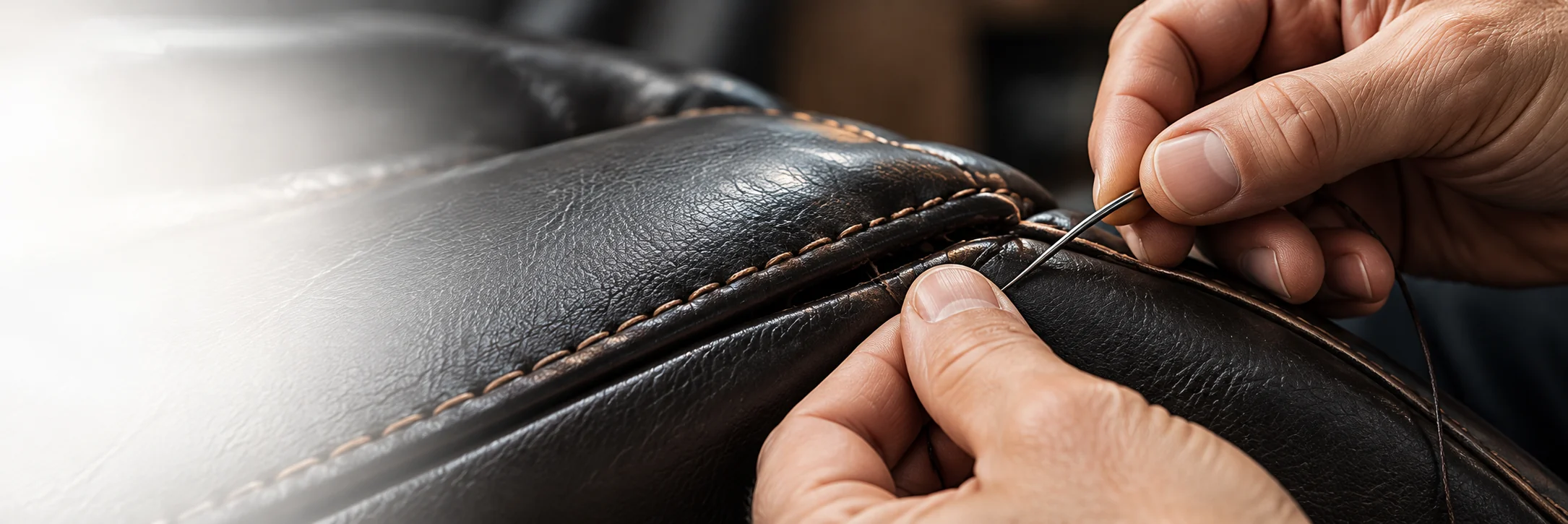 Hands hand-stitching a seam on a home theater seat panel with a curved needle