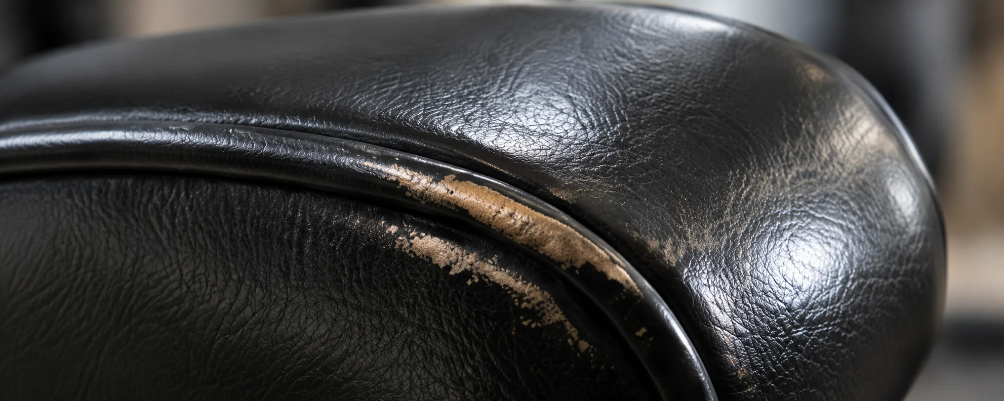 Worn and cracked leather piping running along a cushion edge