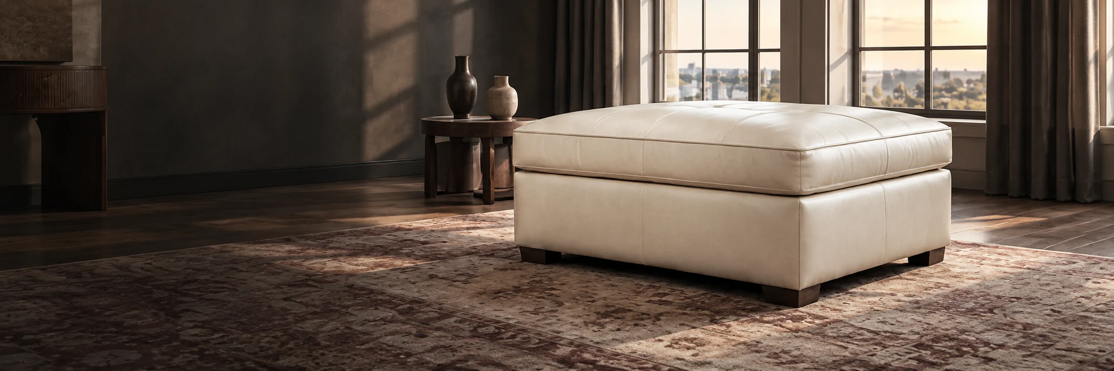 An ivory leather storage ottoman in a paneled room at dusk