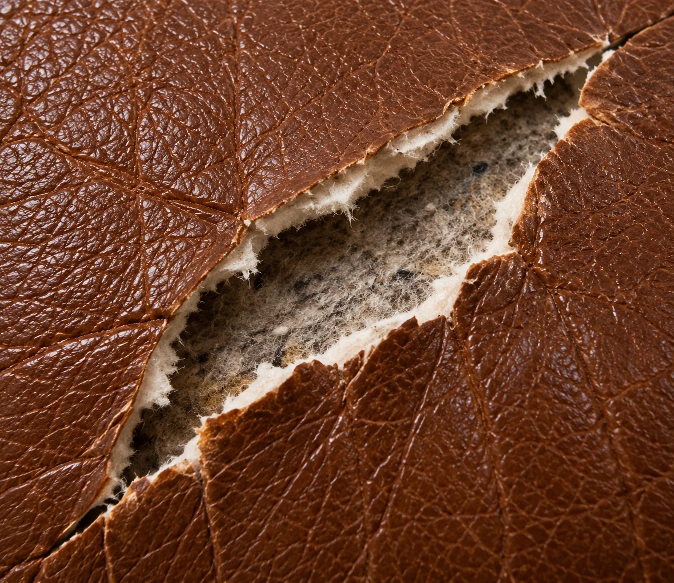 Wide rip with crumbling edges in old leather
