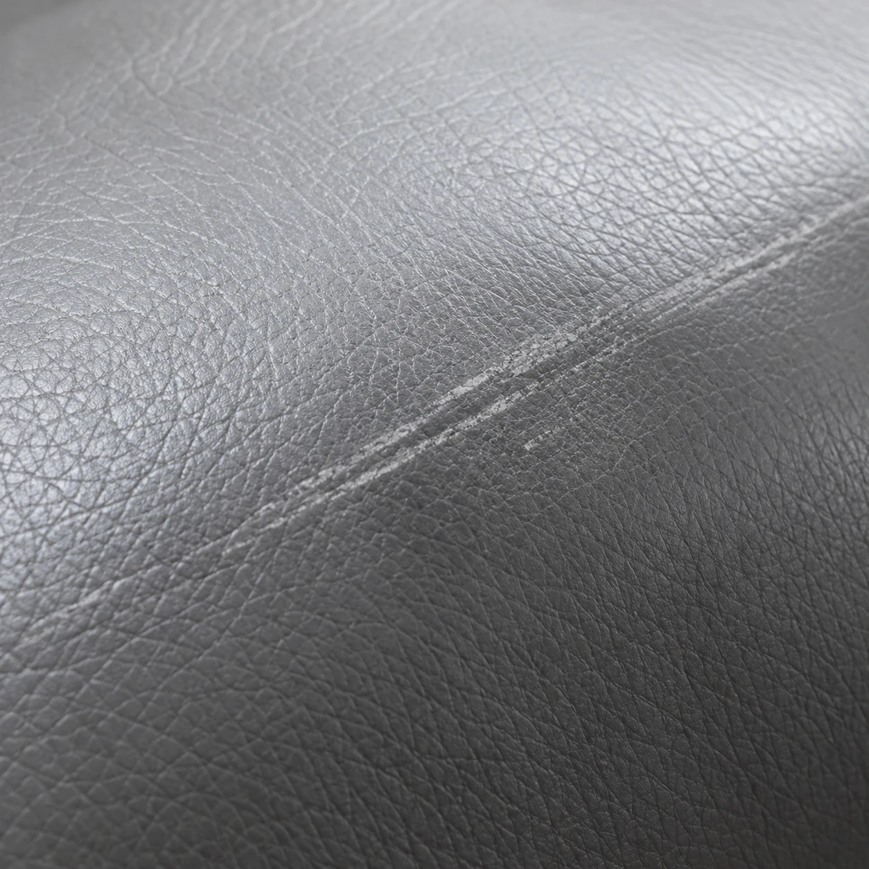 A soft scuff mark rubbed into the surface of gray leather upholstery