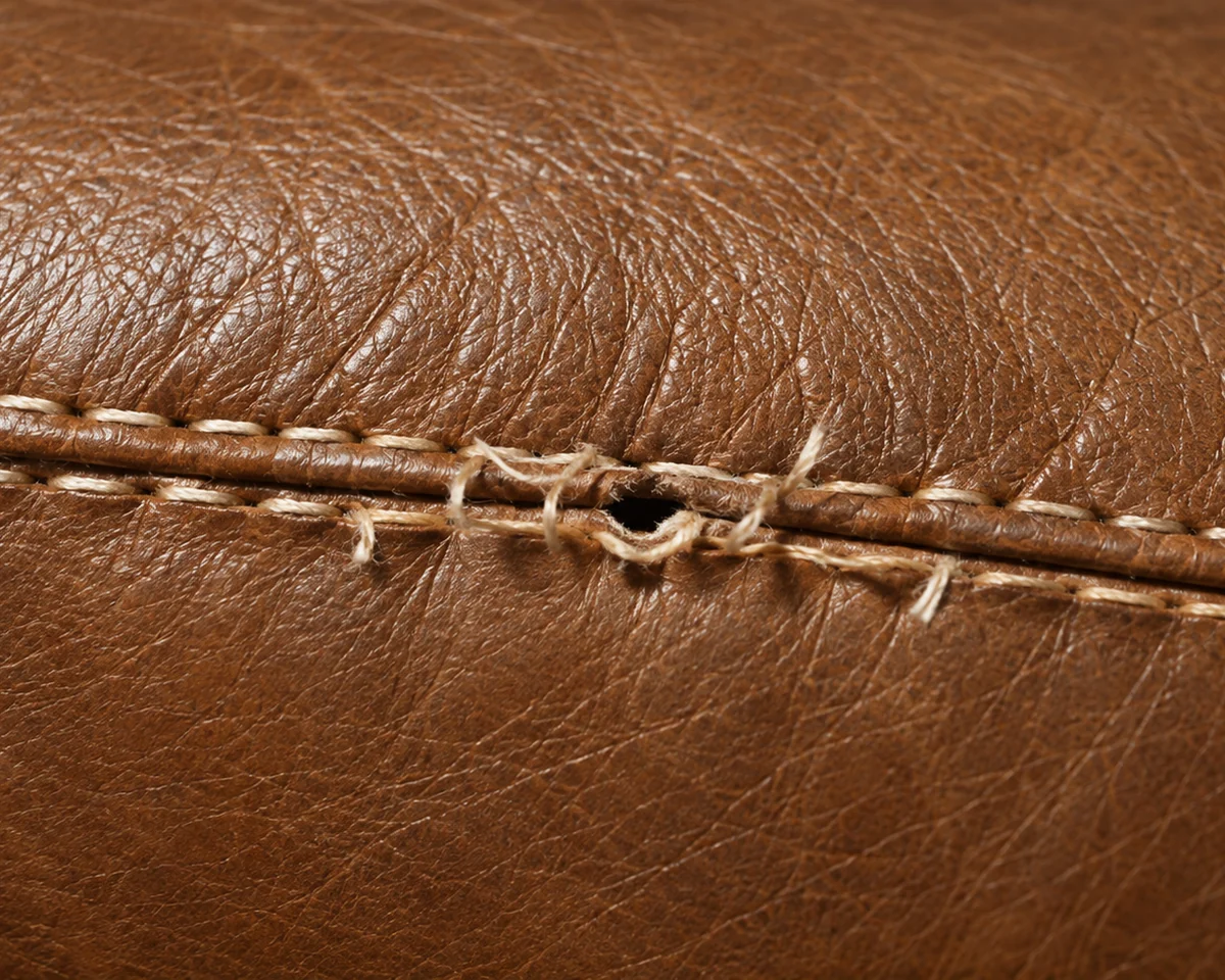 Stitch holes torn on a brown leather seam