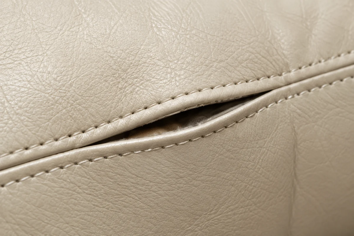 Seam opening along a cream leather cushion
