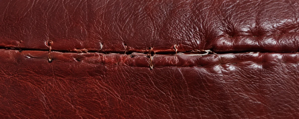 Old stitching and glue in a burgundy seam