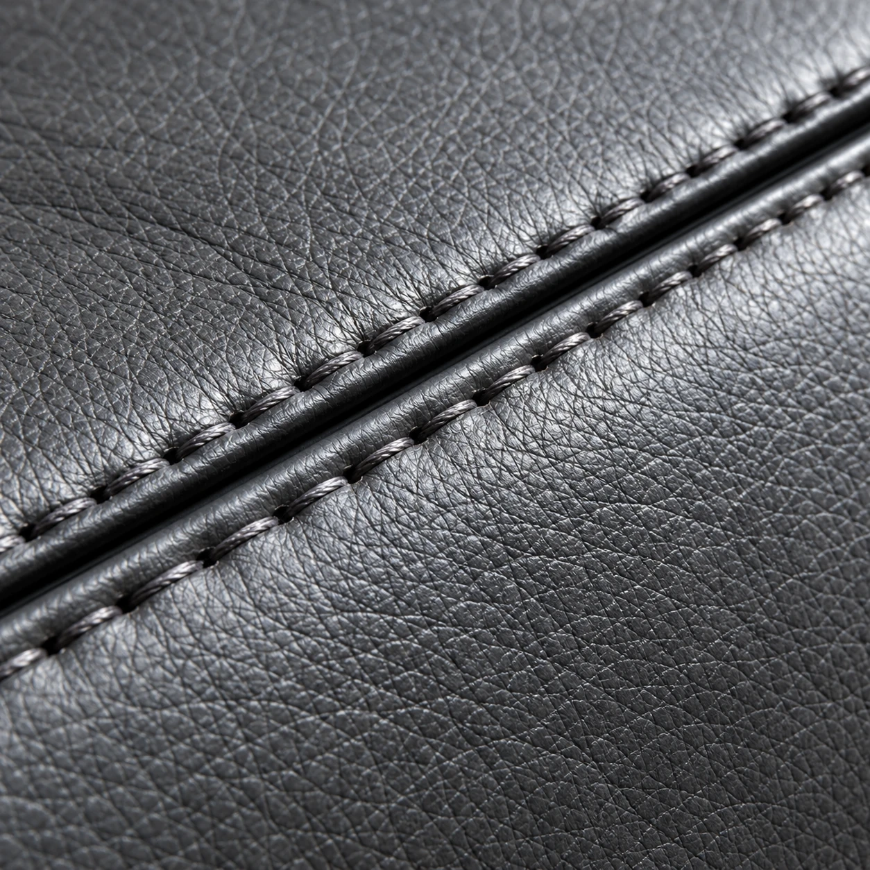 A close view of stitched seam thread along a dark leather panel edge