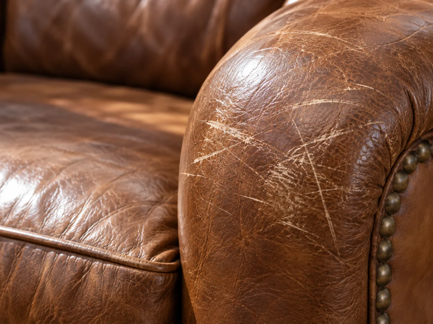 A scratched cognac leather sofa arm before repair