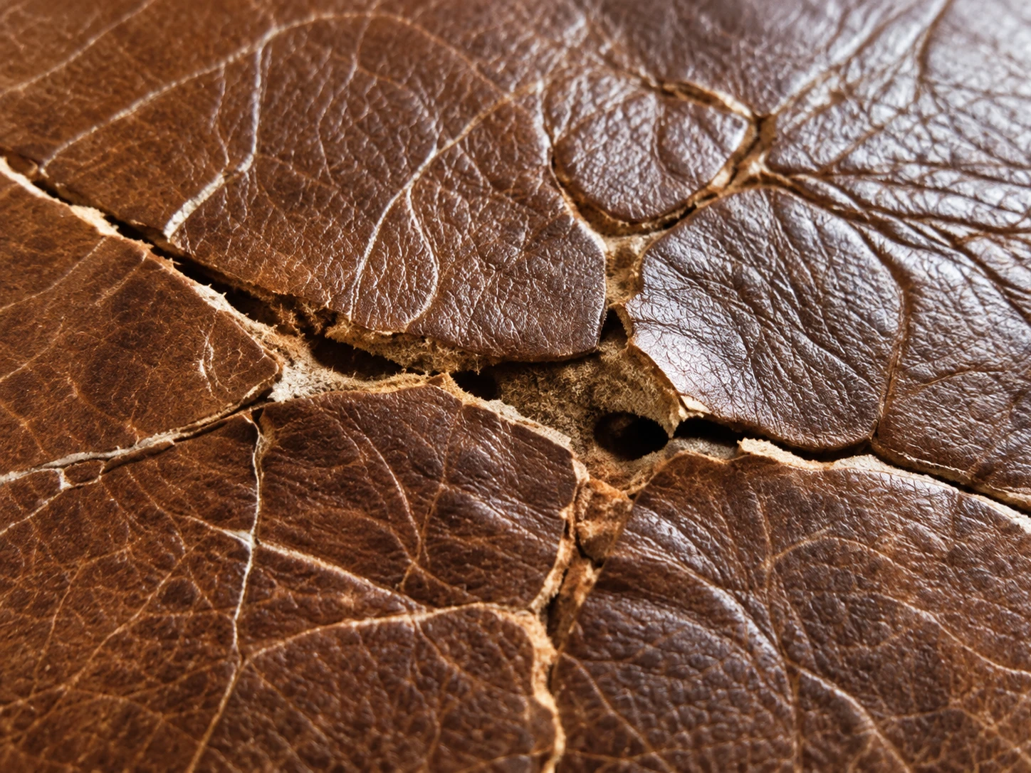 Deep cracks across a brown leather seat