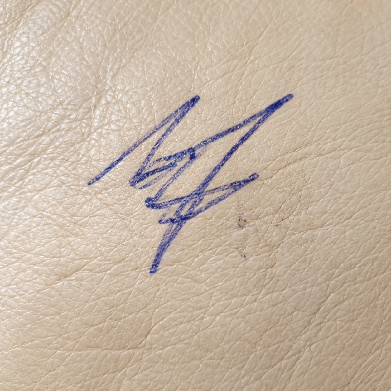 Blue ink pen marks on cream leather