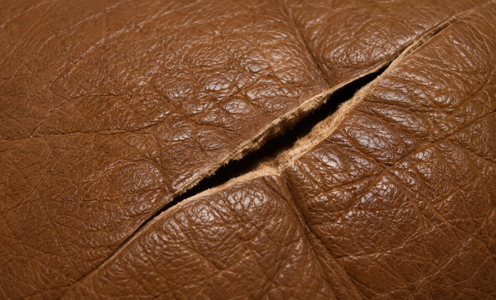 Old tears in dark leather with curled, hardened edges