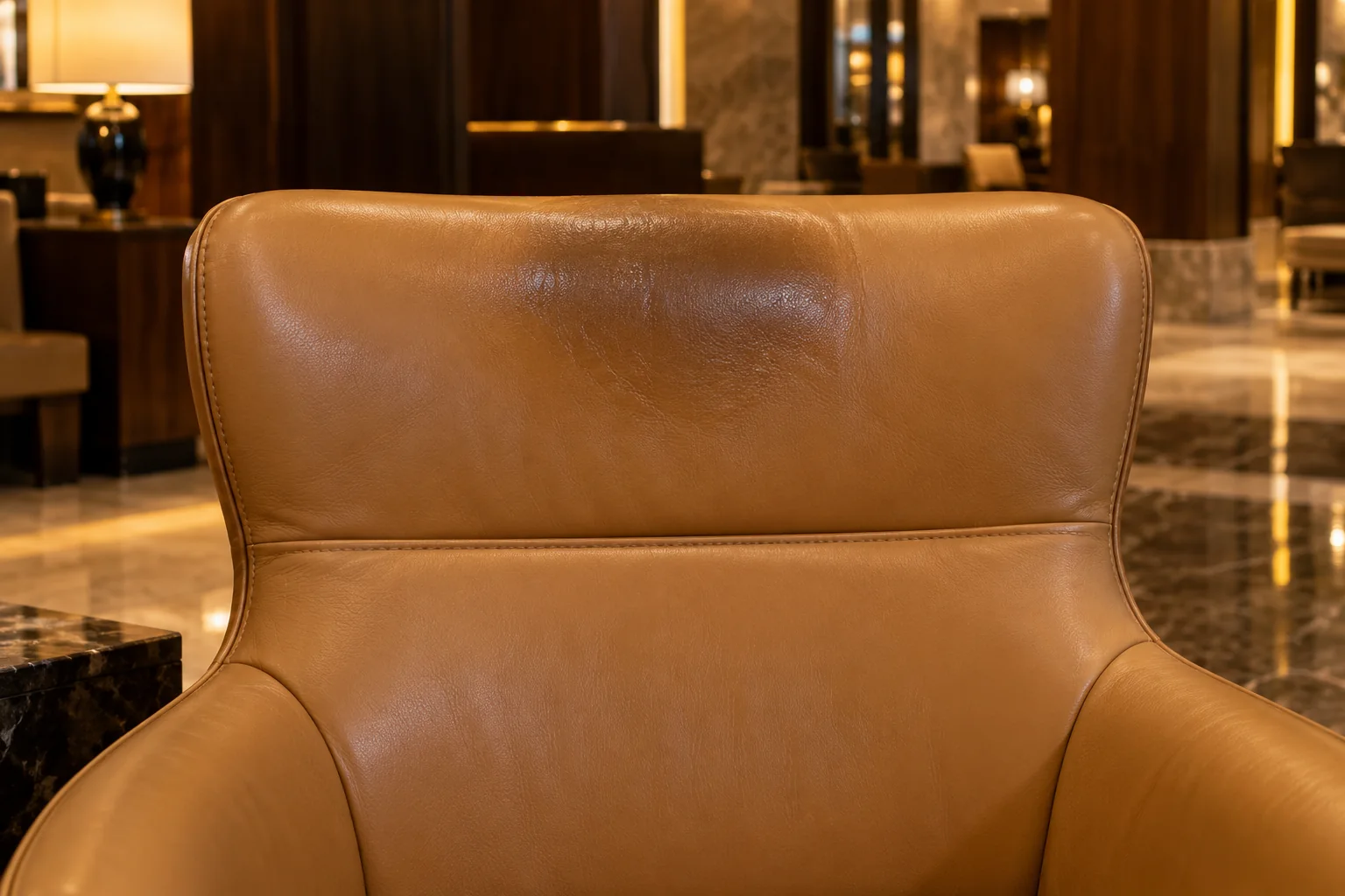A shiny, darkened headrest on a hotel lobby leather chair