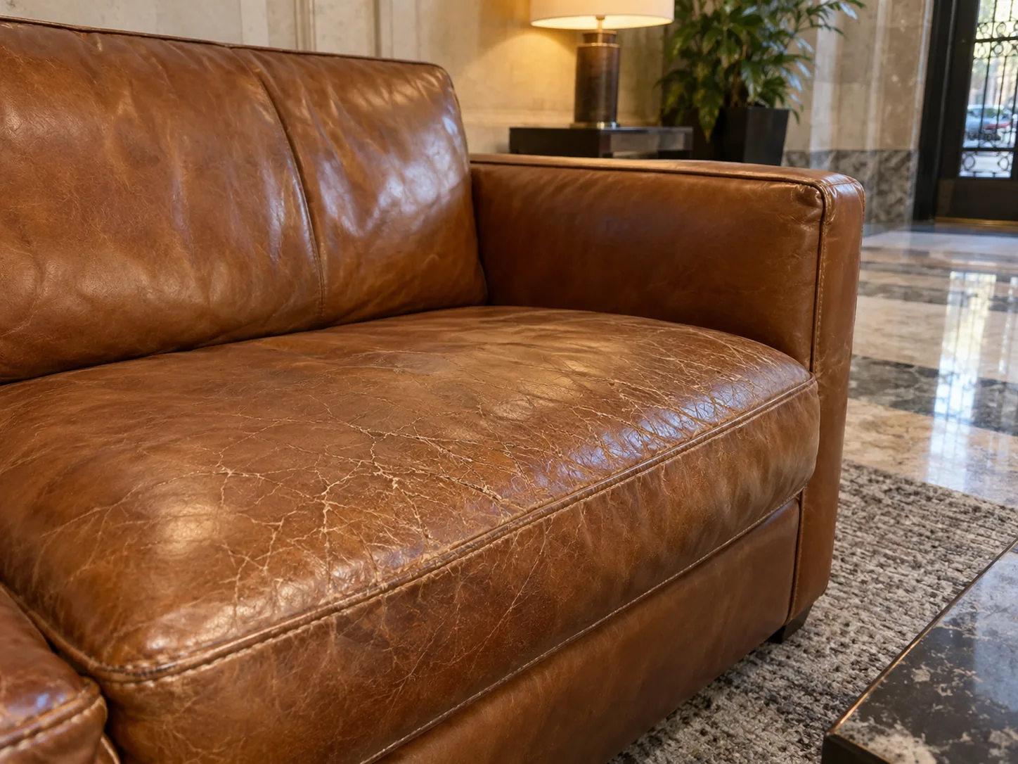 A cracked leather seat cushion on a lobby sofa