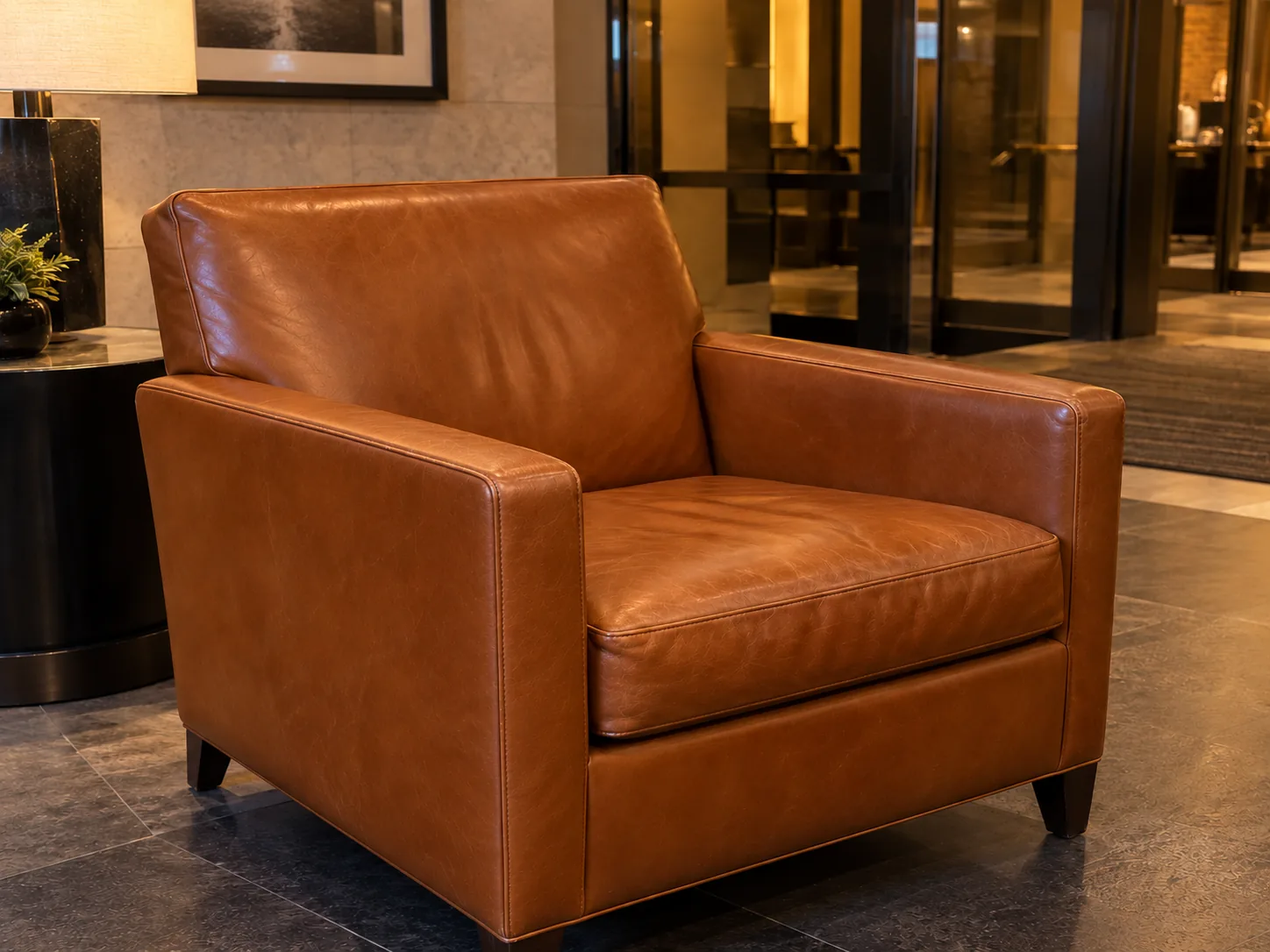 A cognac leather lobby lounge chair with the arm repaired