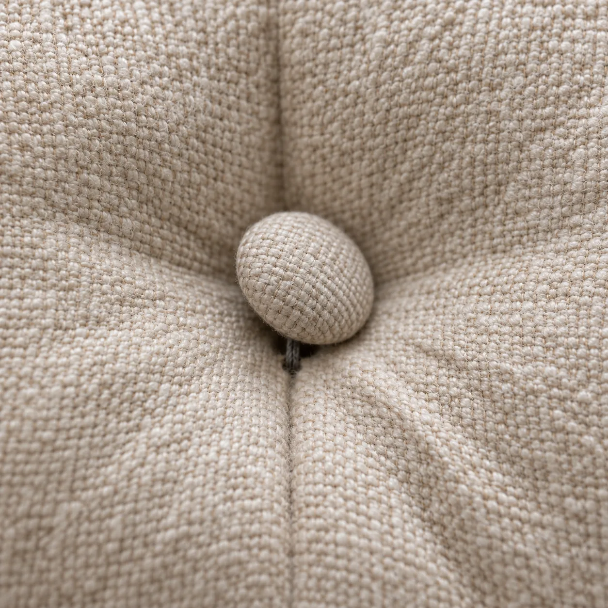 Loose tufting button lifted proud of the face of an upholstered headboard