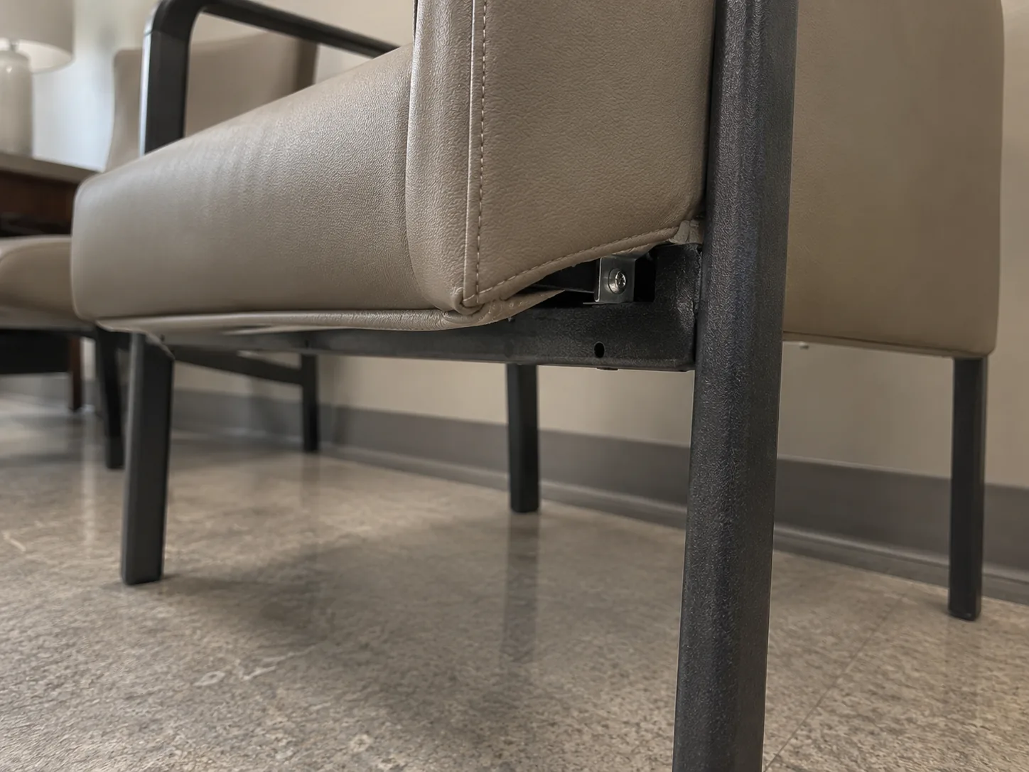 A loose seat panel coming away from a waiting room chair frame