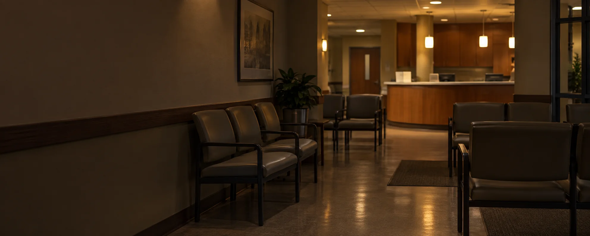 An empty medical office waiting room in the evening, chairs in their rows and the lights low