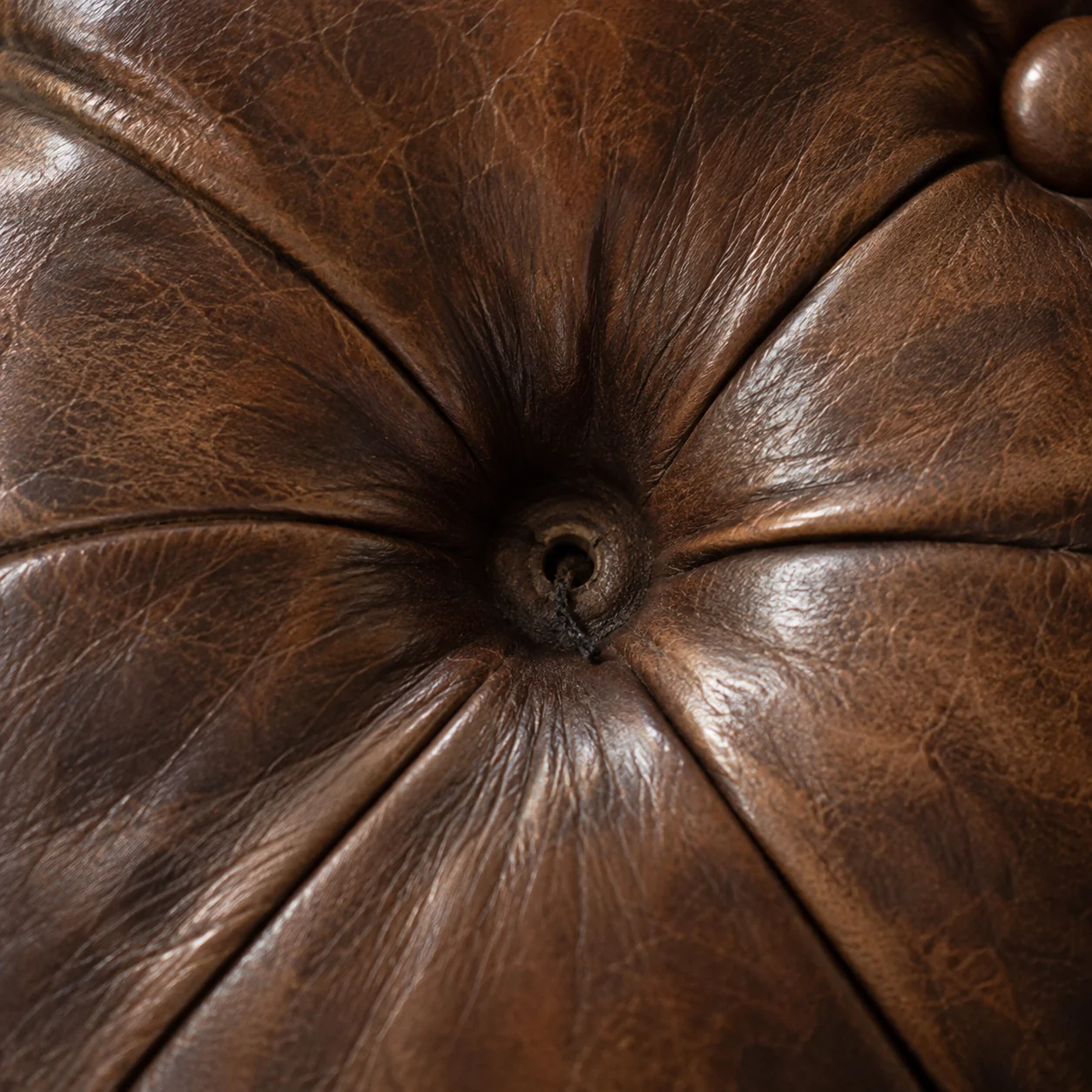 Empty button dimple with twine showing in a deep-buttoned leather back