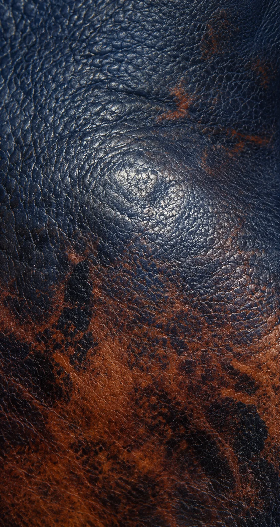 Close-up of warm staining and wear on navy leather