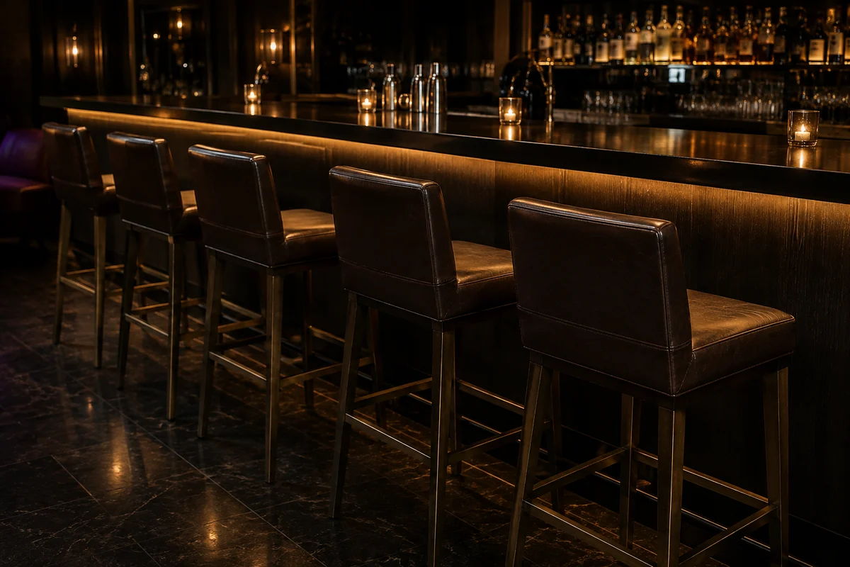 Row of dark leather bar stools along a lit back bar counter