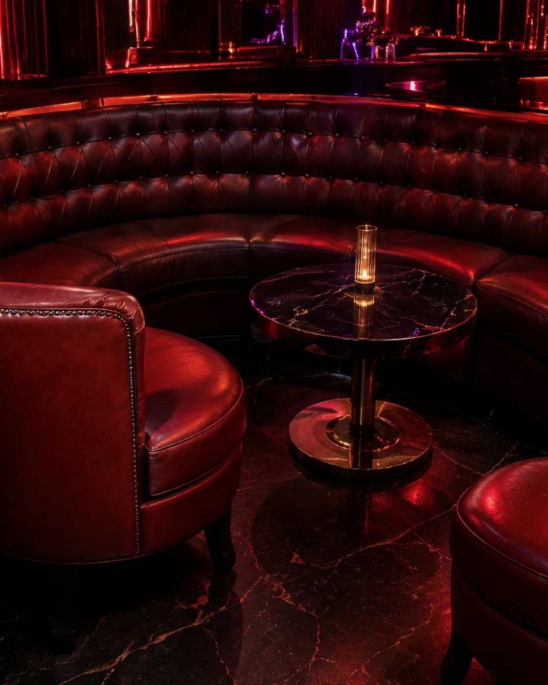 A red leather curved banquette and club chairs in a nightclub lounge
