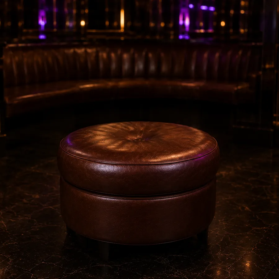 A round tufted leather ottoman on a nightclub floor