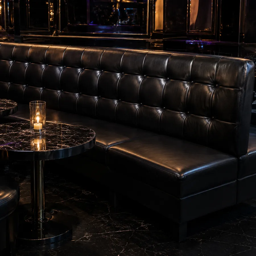A straight black tufted wall banquette with marble tables