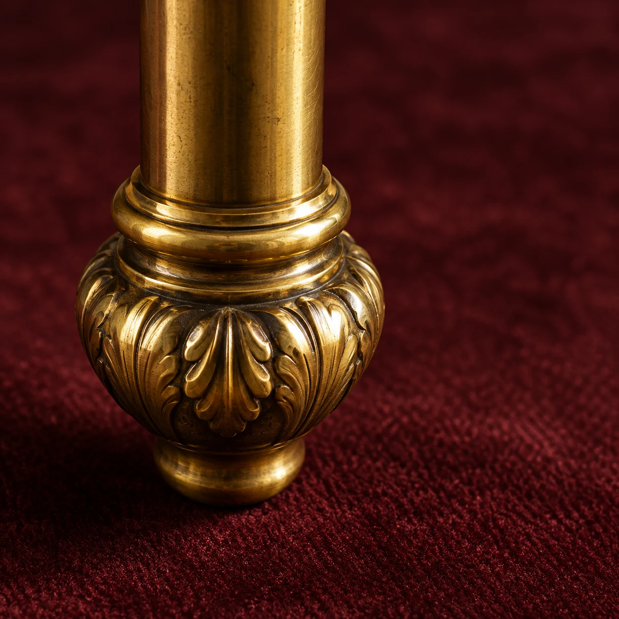 Ornate cast brass ferrule at the foot of a chair leg on burgundy velvet