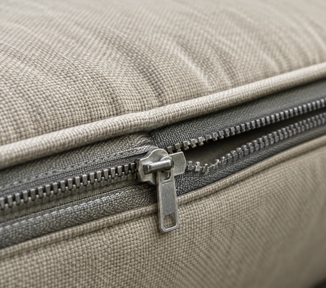 Moulded zipper slider on a beige outdoor cushion seam