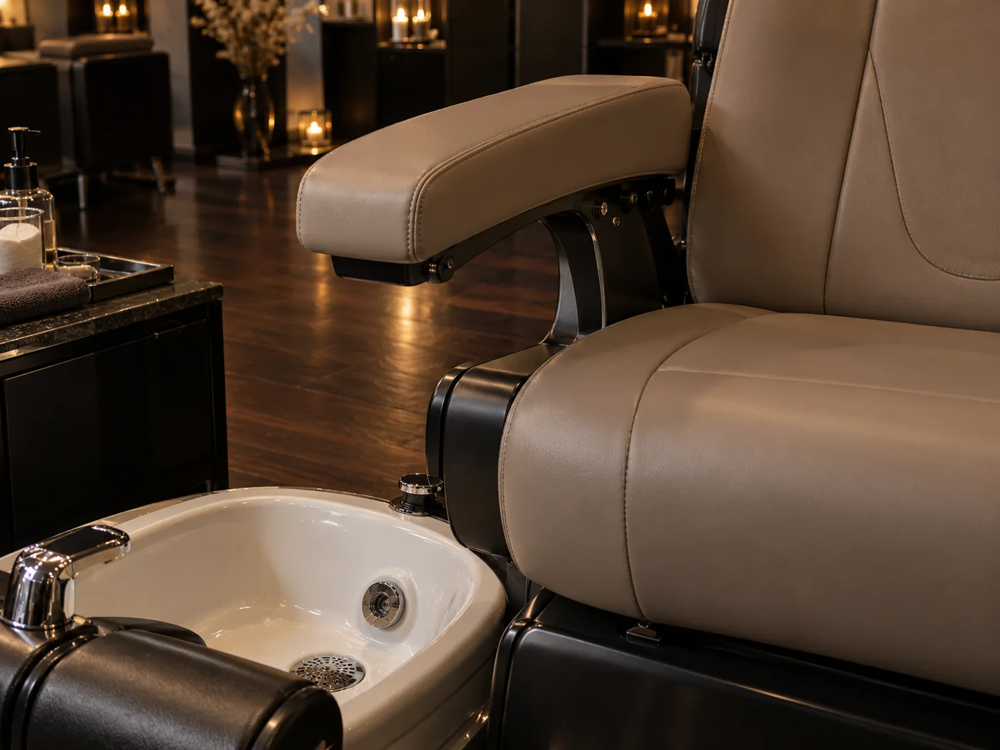 The padded arm and seat of a taupe pedicure chair above its foot tub