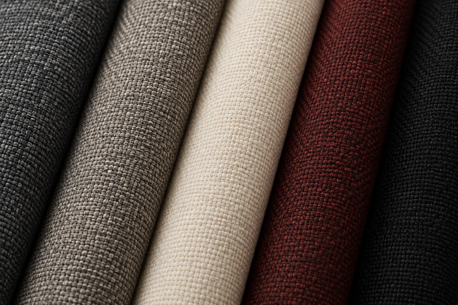 Rolls of woven performance upholstery fabric in charcoal, gray, oatmeal and wine