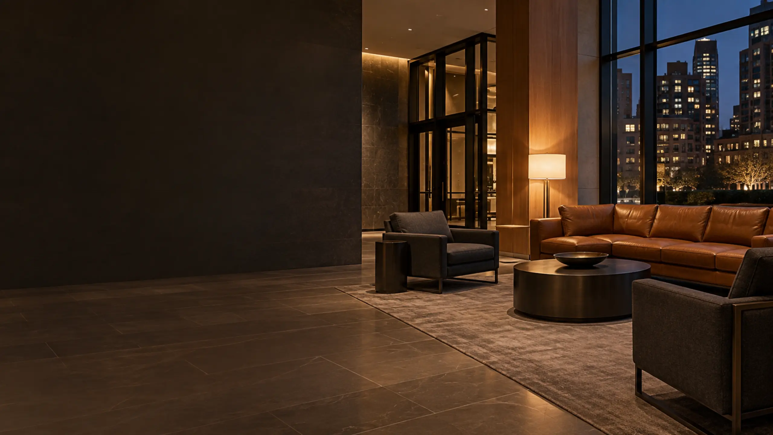 A quiet residential lobby in the evening with cognac leather seating by the windows