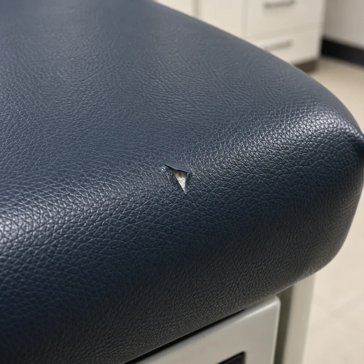A small puncture in the navy vinyl of a treatment table