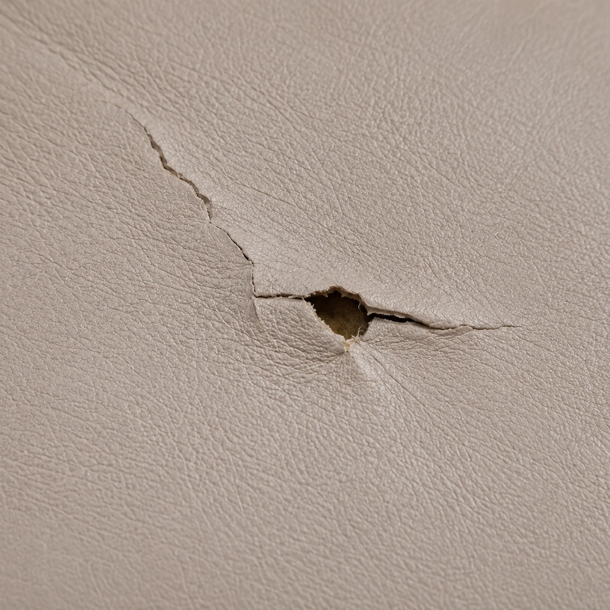 A small puncture in taupe dental chair vinyl