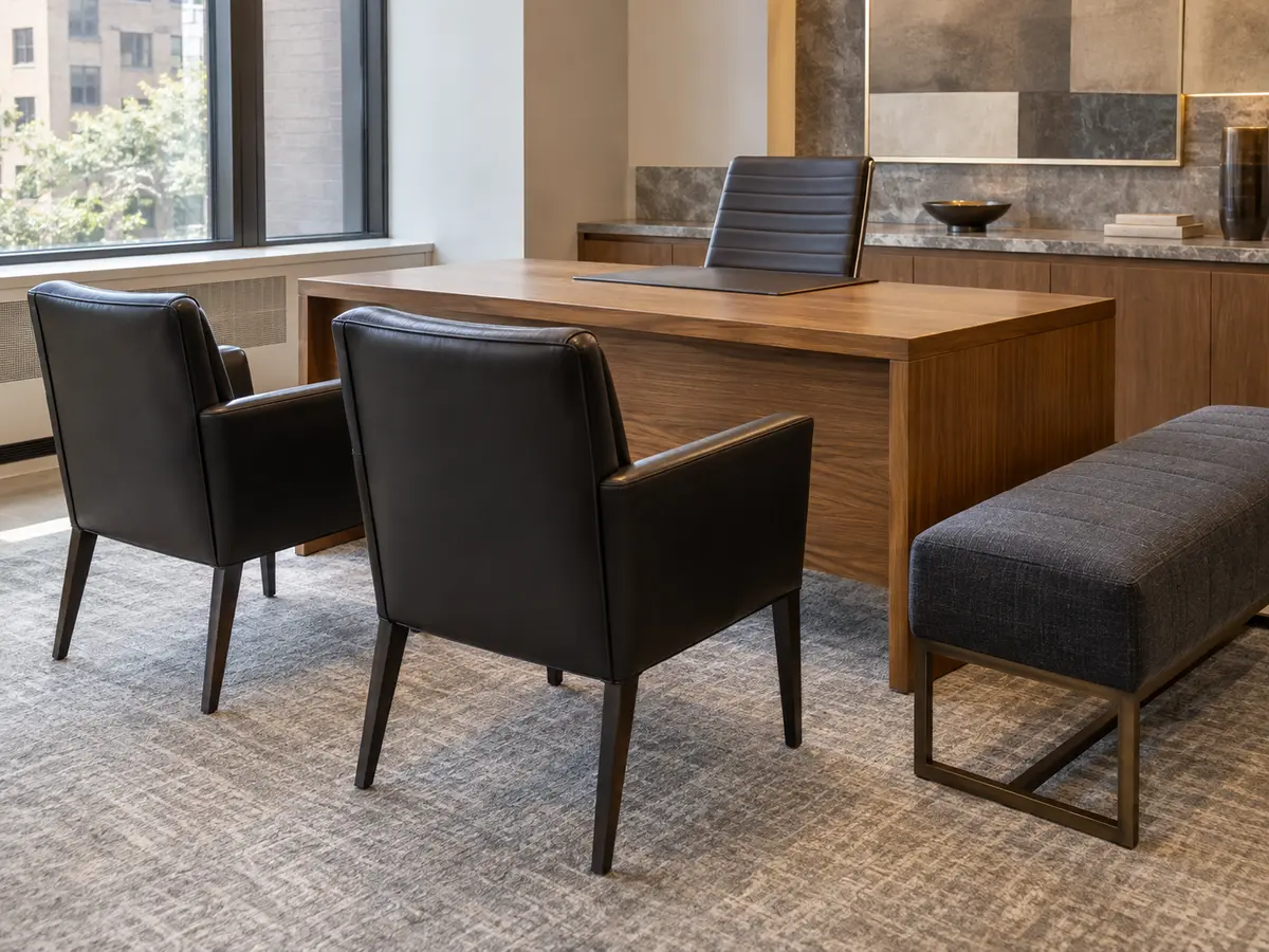 Black leather guest chairs at a desk in a Queens leasing office
