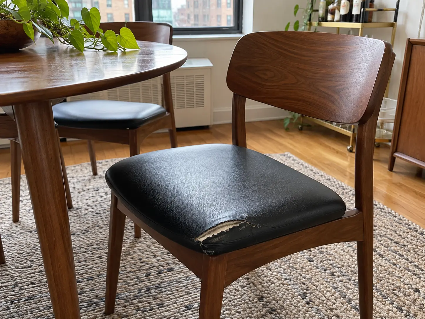 Black dining chair seat torn at the front edge