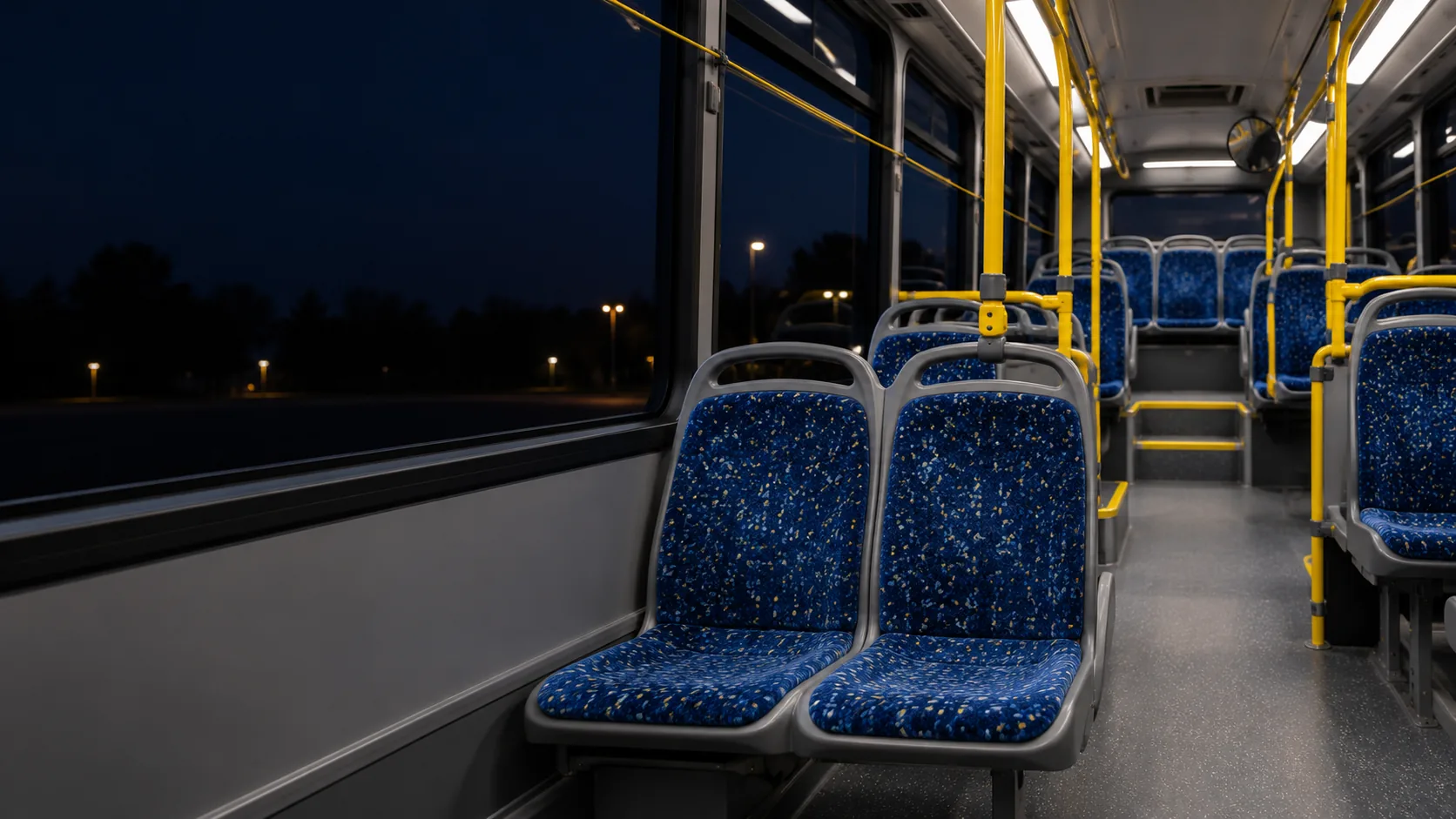 A bus interior in the evening with every seat uniform under the lights