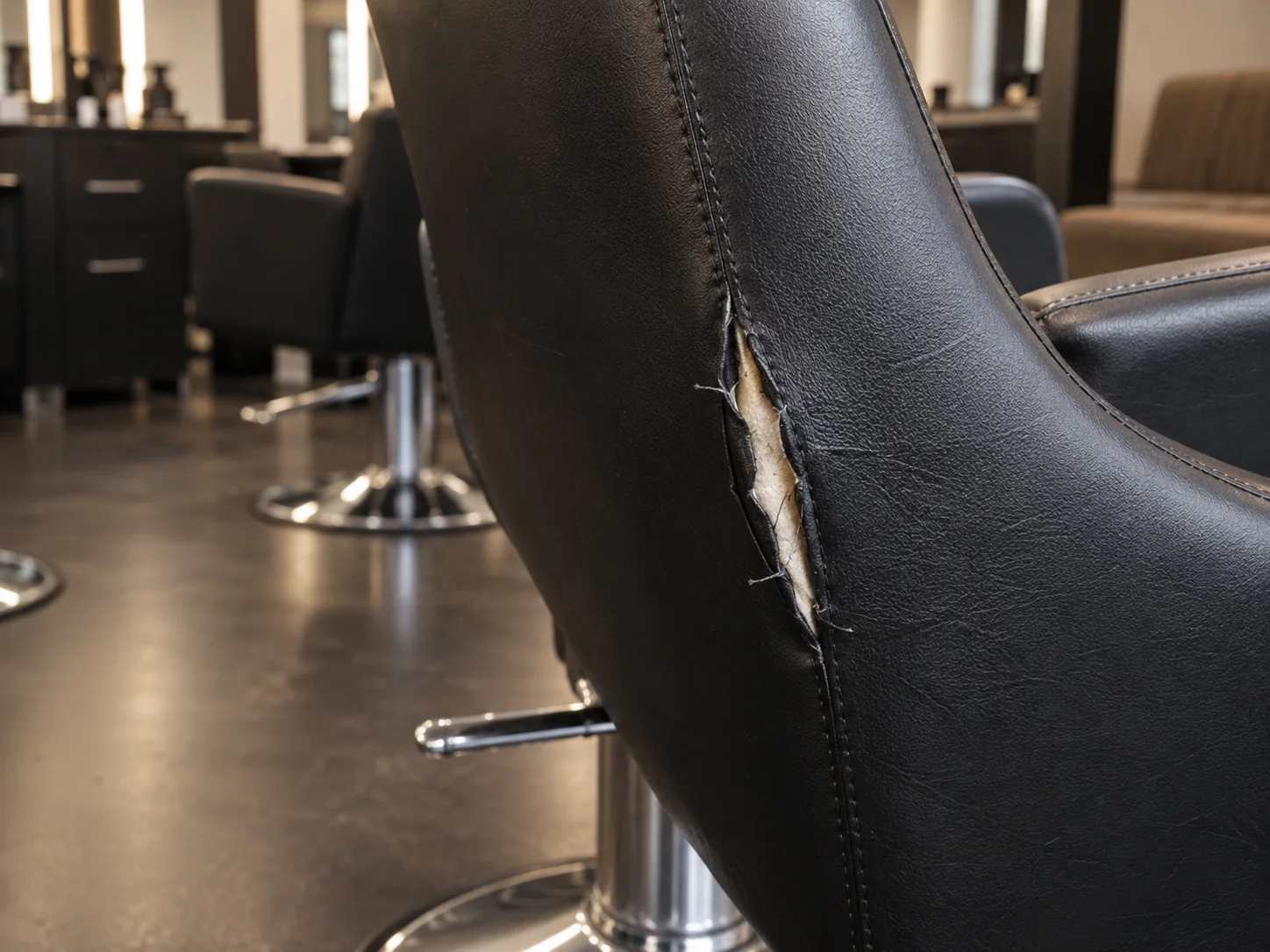 A split seam on the backrest of a black salon chair