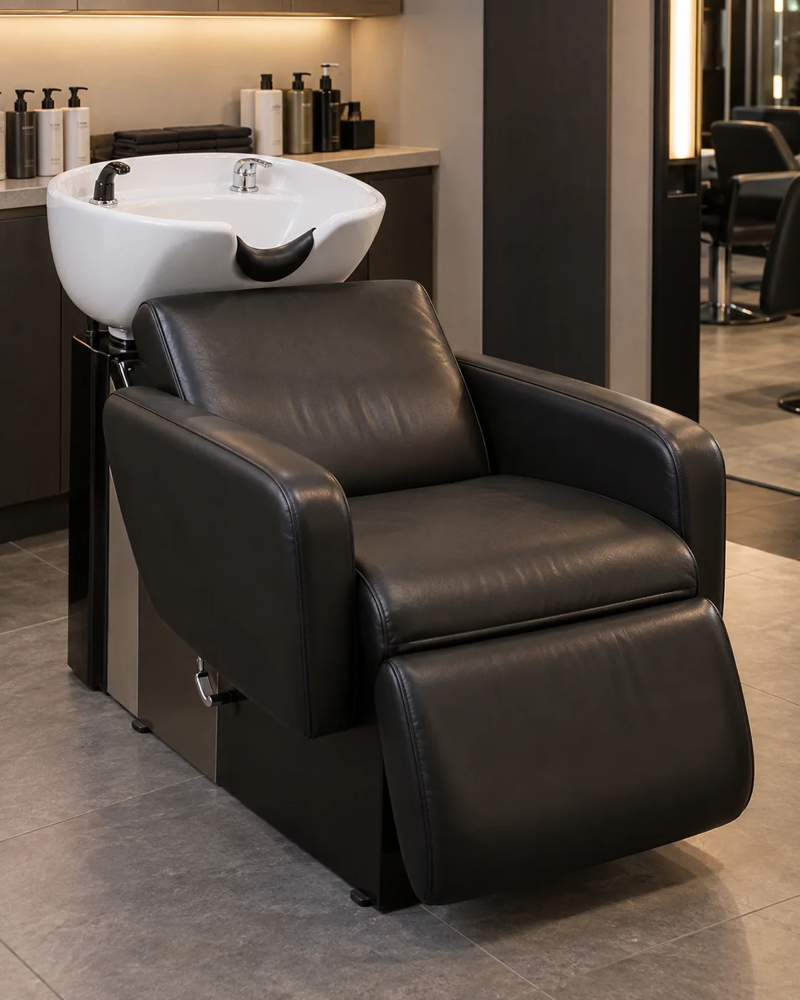 Black salon shampoo chair with leg rest at a backwash unit