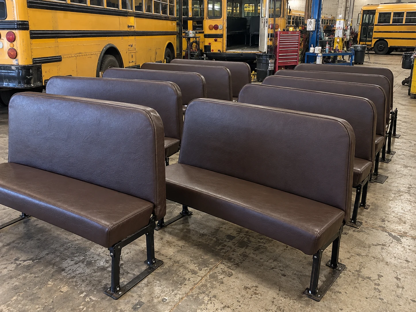 Finished school bus benches staged in rows in the workshop