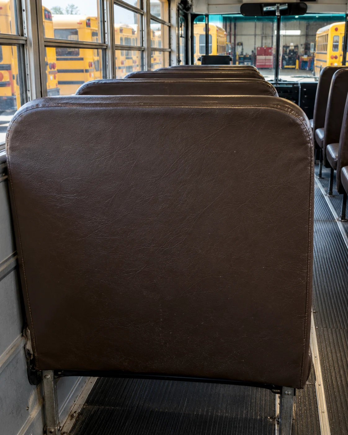 The back panel of a school bus seat seen from the row behind