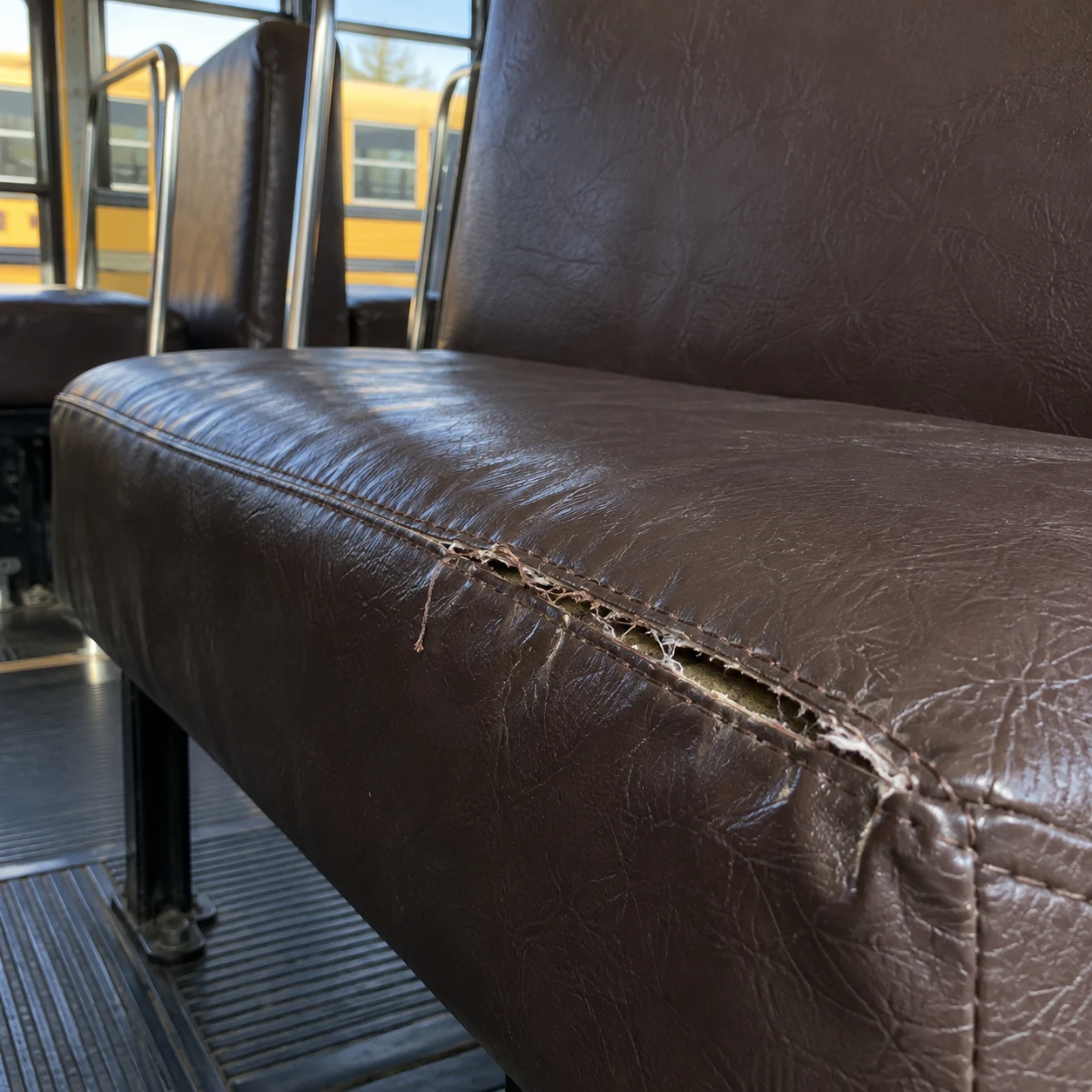 A split seam along the stitch line of a school bus seat