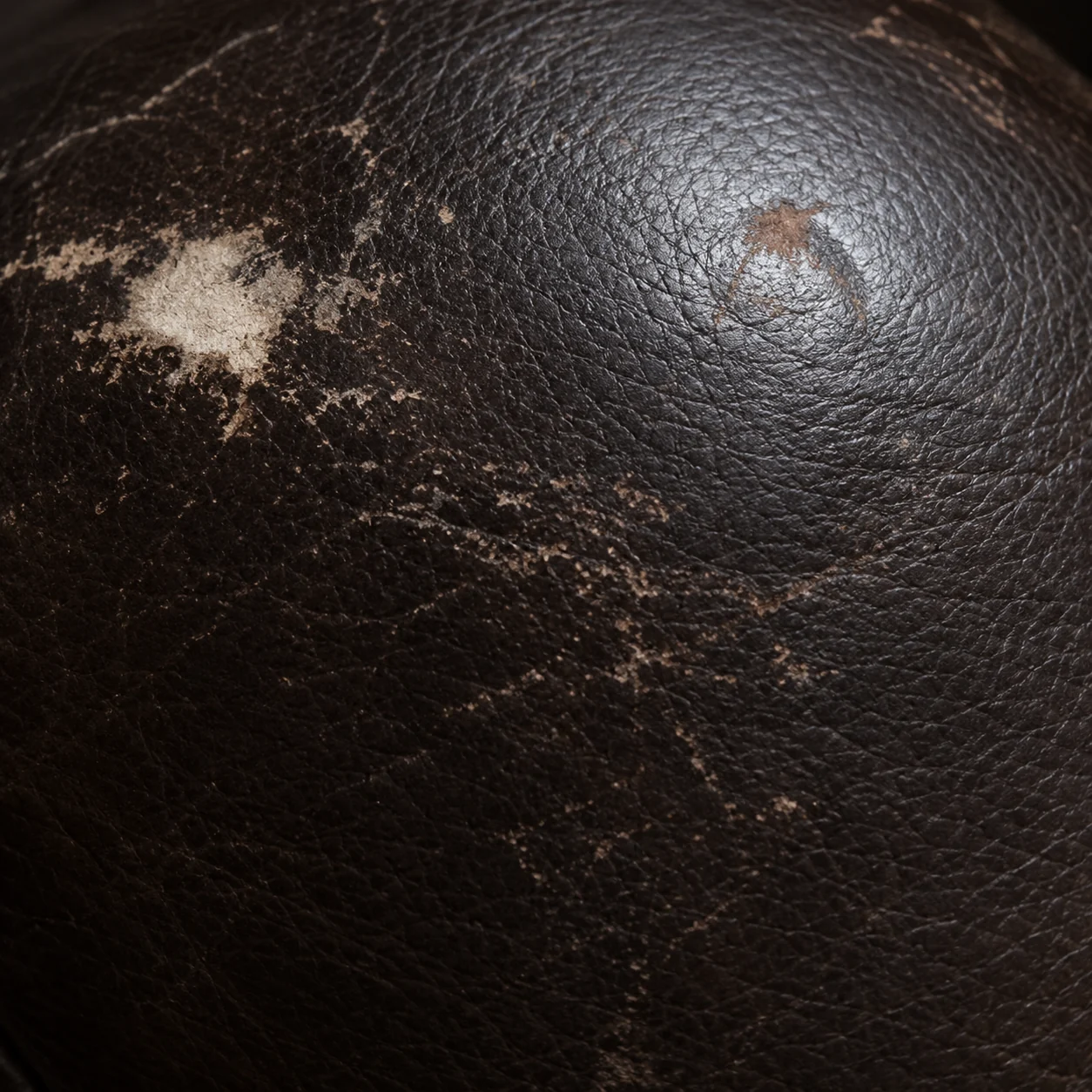 Cluster of scratches and a scuff across dark home theater seat leather