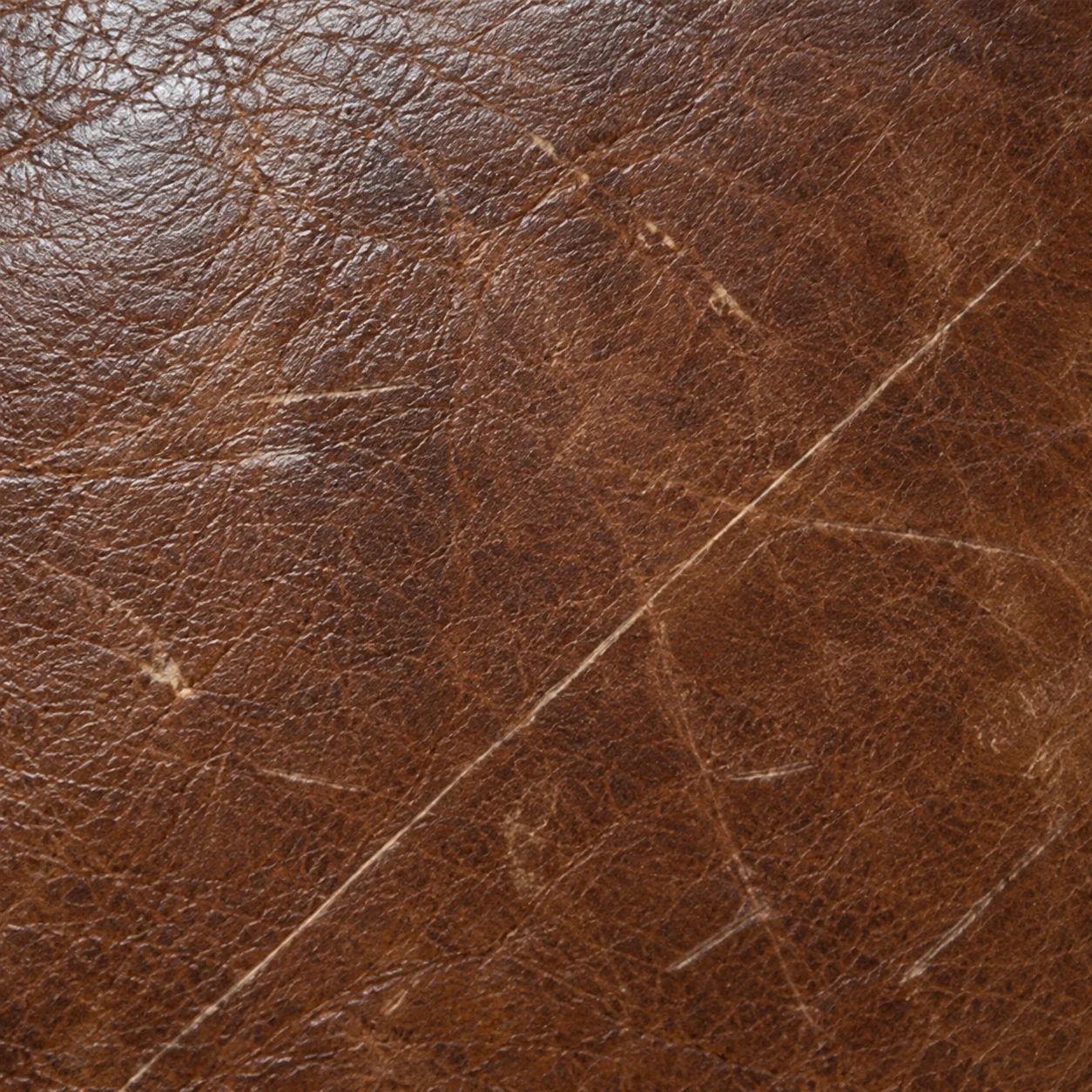 Pale scratch lines across the grain of an antique leather sofa