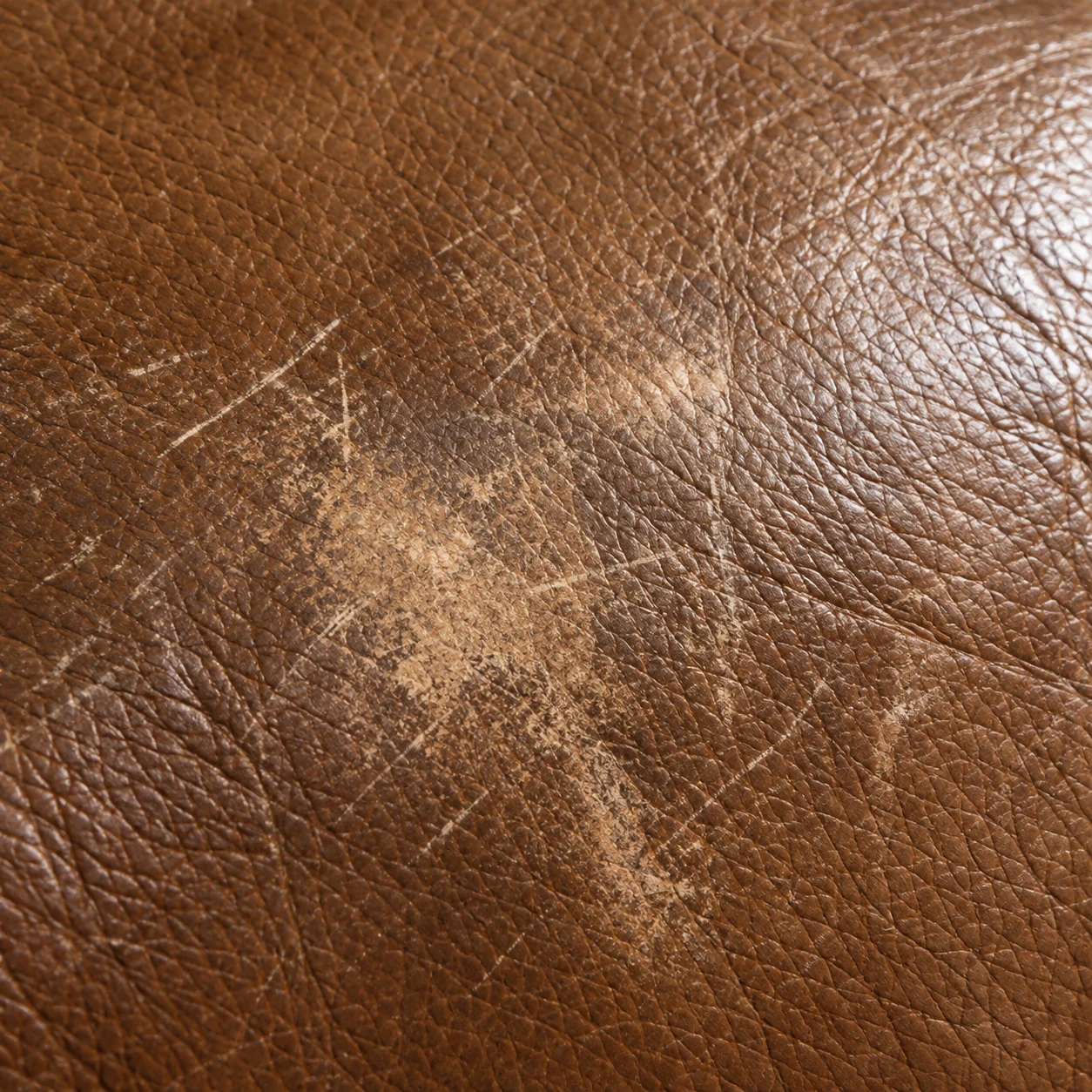 Scratched and scuffed brown leather panel