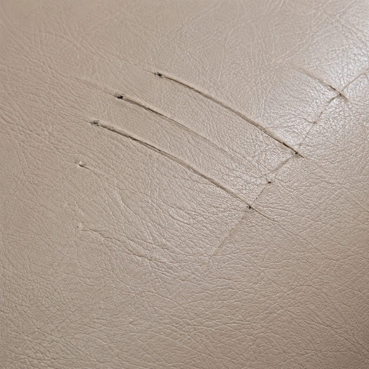 Fine scratches across pale dental chair vinyl