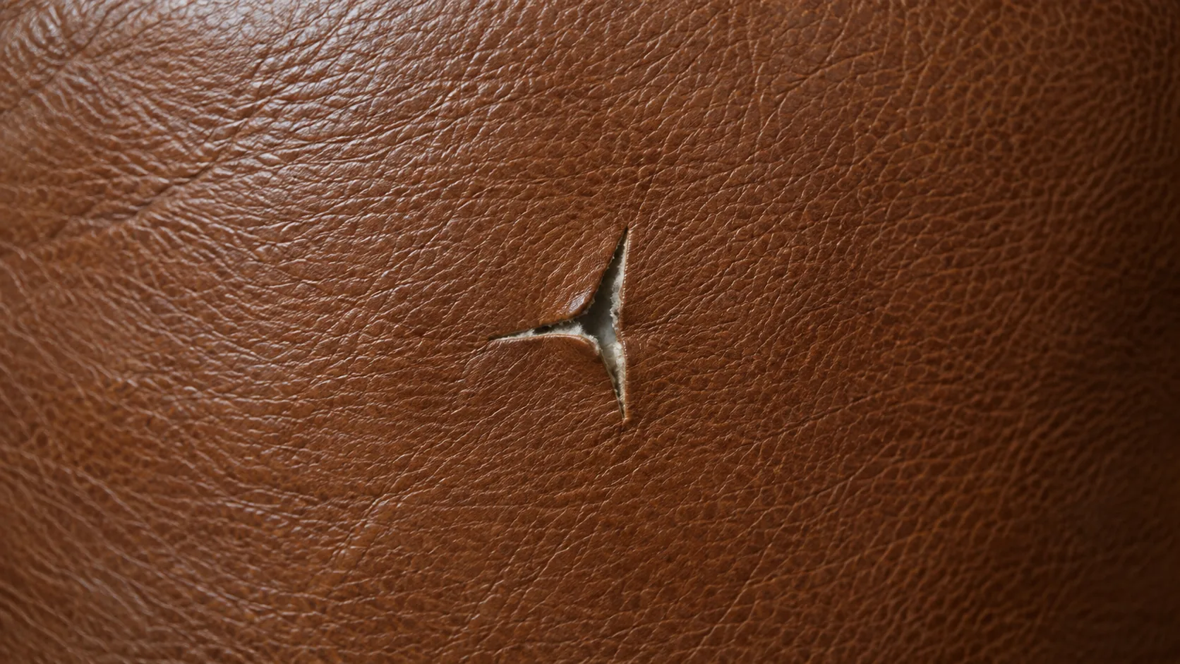 Small three-point tear in tan leather