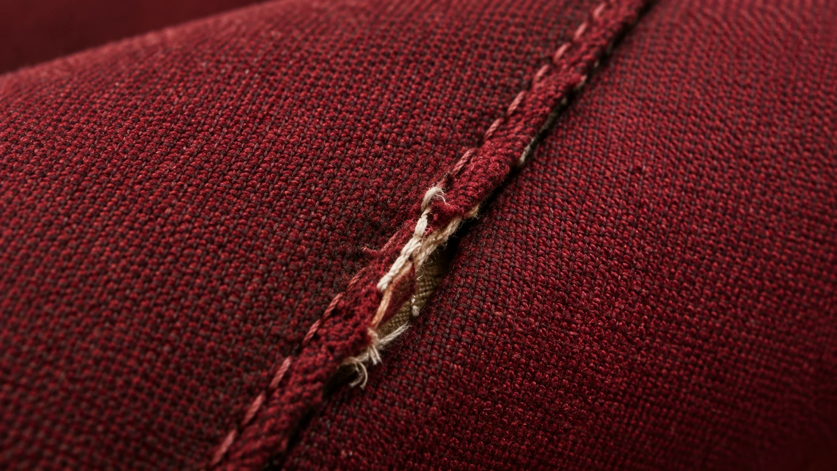 Split seam on an auditorium seat cover with the filling showing